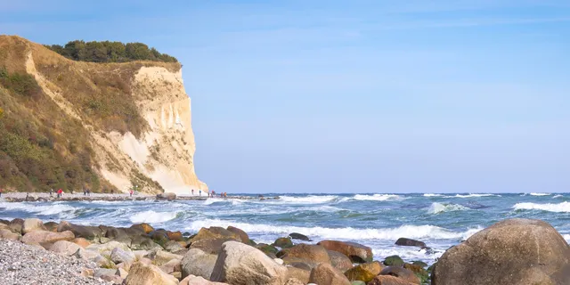 Chalk cliffs on the island of Rügen with waves and people in front