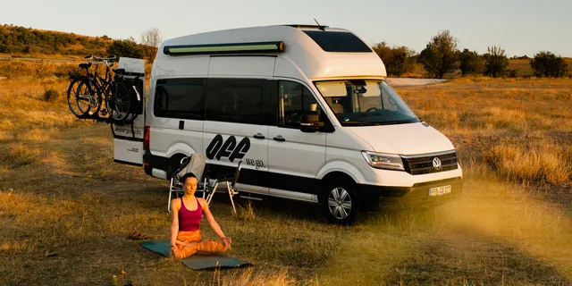 Woman doing yoga before the camper