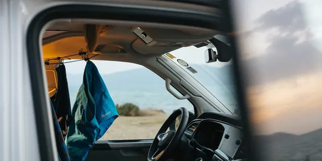 In a camper parked on the beach, bathing clothes dry on a linen line.