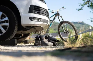 In front of a white off camper there are hiking shoes and a helmet at the camping in the Dolomites